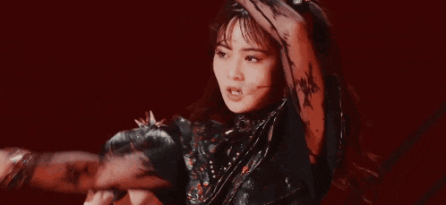 a woman in a black dress is dancing on stage with a microphone .