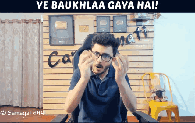 a man sitting in a chair with the words ye baukhlaa gaya hai behind him
