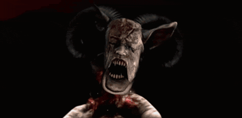 a close up of a demon with horns and blood on its face
