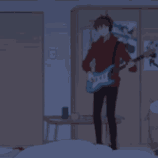 a man playing a guitar in a bedroom with posters on the wall