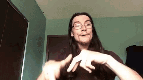 a man with long hair and glasses making a funny face