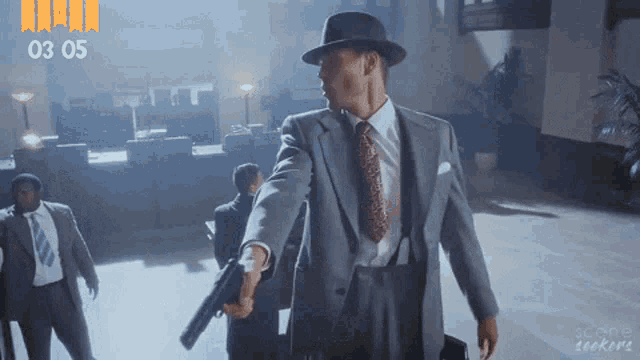 a man in a suit and tie is pointing a gun at the camera with the number 03 05 behind him