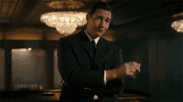 a man in a suit and tie is holding a glass in his hand