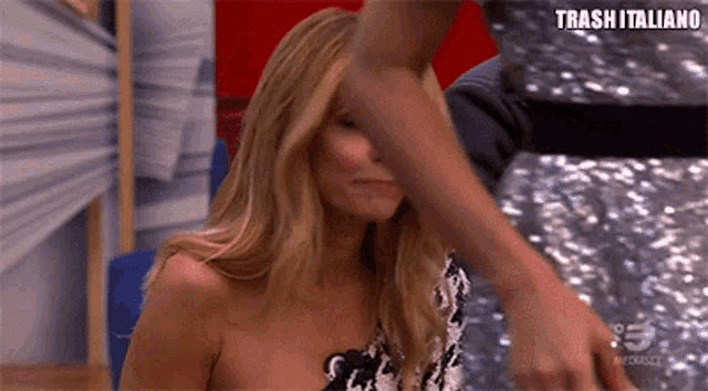 a woman in a black and white dress is being touched by a man 's hand while sitting on a chair .