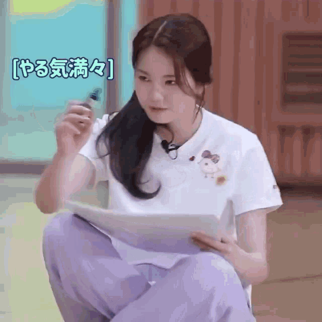 a woman is kneeling down while holding a piece of paper and a pen .