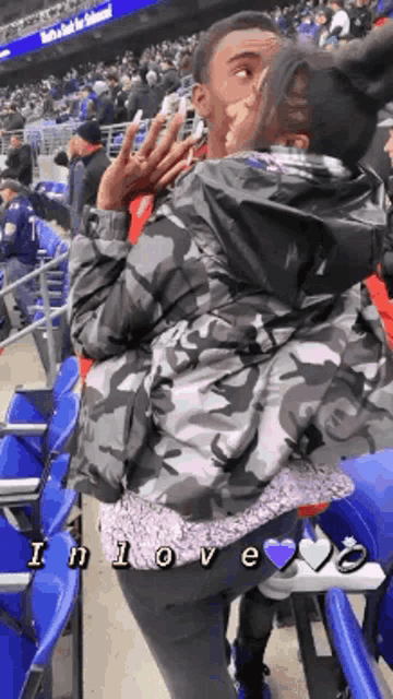 a man and a woman are kissing in the stands at a sports game .