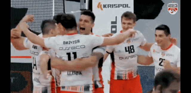 a group of volleyball players are hugging each other in front of a krispol logo