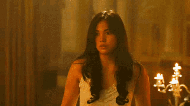a woman in a white dress is standing in a dark room