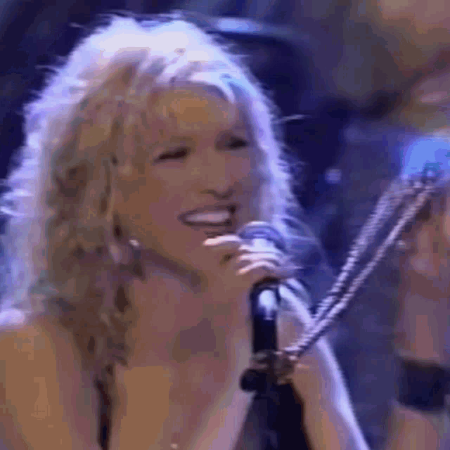 a close up of a woman singing into a microphone on a stage .