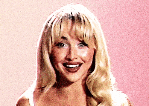 a woman with blonde hair and bangs is smiling and looking at the camera
