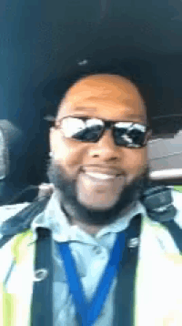 a man wearing sunglasses and a safety vest is smiling .