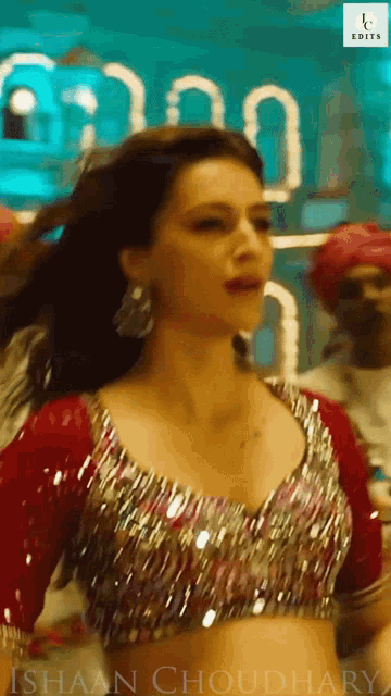 a woman in a red and silver crop top is dancing in front of a sign that says edits