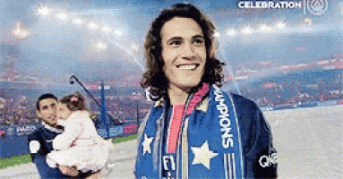 a man wearing a scarf that says champions is holding a little girl