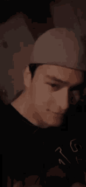 a man wearing a gray hat and a black shirt is smiling .