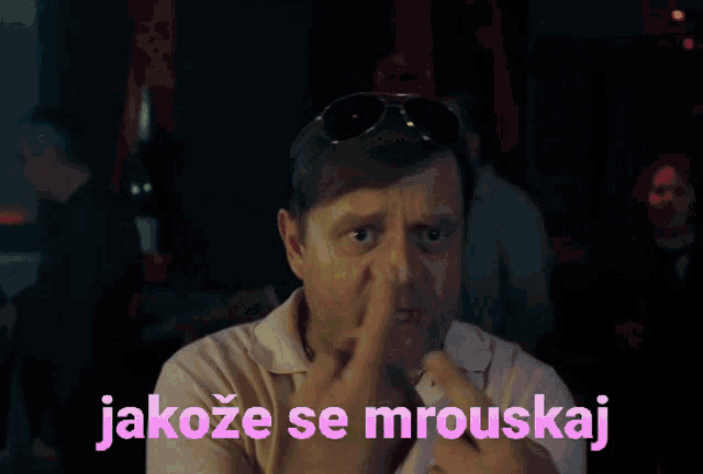 a man covering his nose with his hand with the words jakoze se mrouskaj written in pink