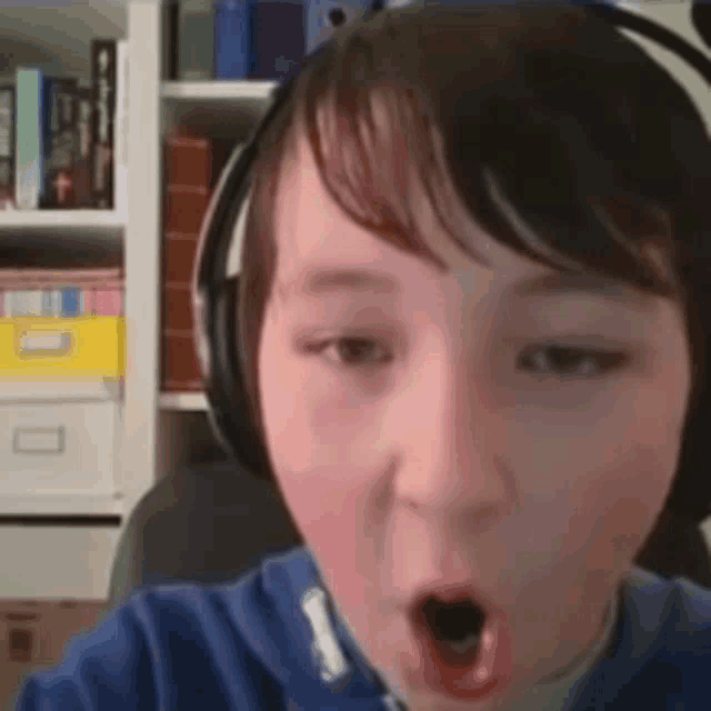 a young boy is wearing headphones and making a funny face .