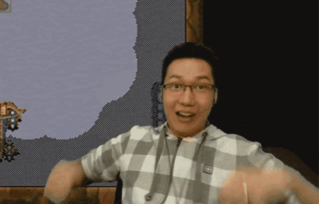 a man wearing glasses and a plaid shirt is standing in front of a screen