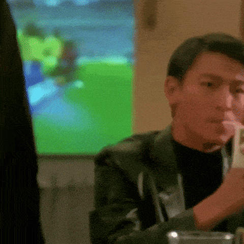 a man in a black jacket is sitting at a table with a cell phone in his hand ..