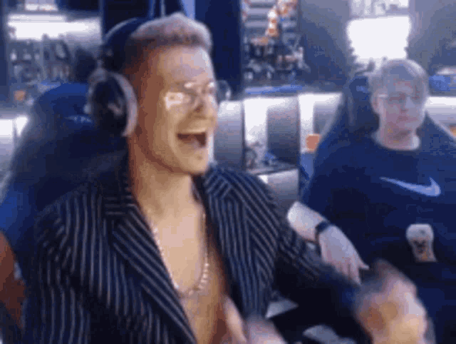 a man in a suit and headphones is sitting in a chair and laughing .