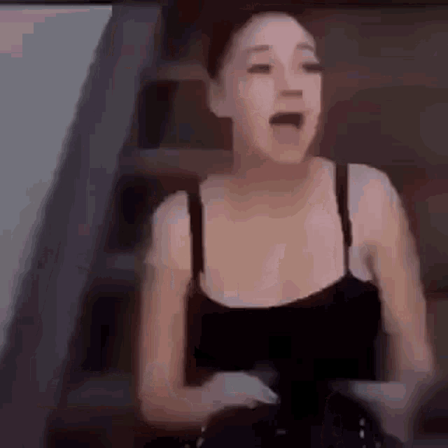 a woman in a black tank top is standing on stairs .