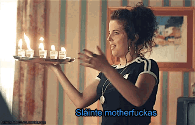 a woman is holding a tray of lit candles and says slaine motherfuckas