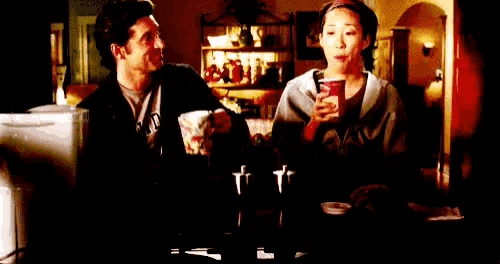 a man and a woman are sitting at a table holding cups of coffee