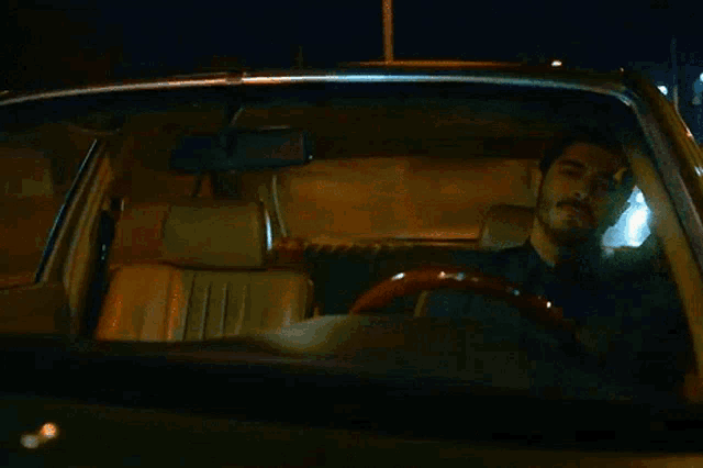 a man is driving a car at night and smoking