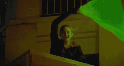 a woman is holding a green glowing object in her hand .