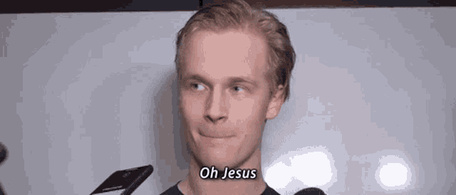 a young man is talking into a microphone and says oh jesus .
