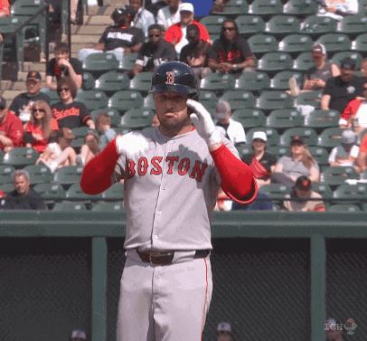 a baseball player wearing a boston jersey holds his helmet up