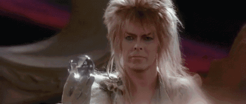 a man with a wig is holding a glass ball in his hand .
