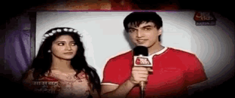 a man and a woman are standing next to each other while a man is holding a microphone .