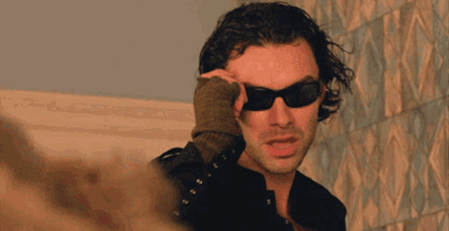 a man wearing sunglasses and a knitted glove
