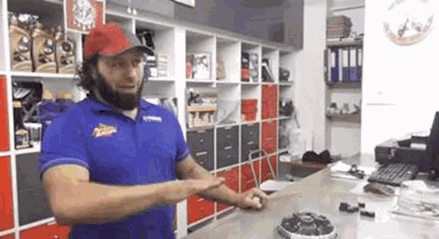 a man in a blue shirt and red hat is standing in a store .