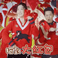 a man and a woman in red sweaters are dancing with chinese writing