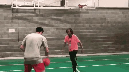 a man in a grey shirt is playing basketball with a woman in a pink shirt