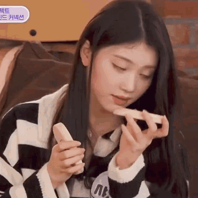 a woman in a striped sweater is eating a piece of pizza .