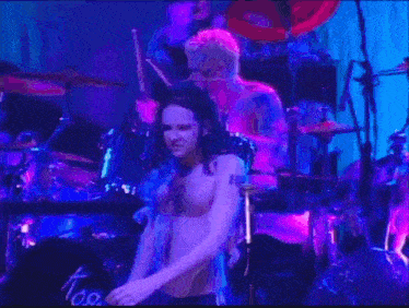 a shirtless man is singing into a microphone on a stage