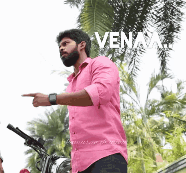 a man in a pink shirt is pointing at something with the word venaa written above him