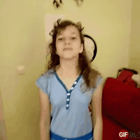 a girl in a blue shirt is standing in front of a red couch