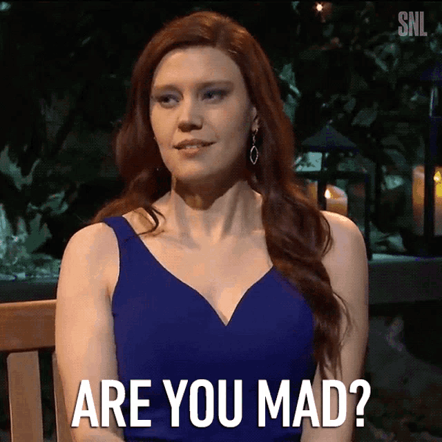 a woman in a blue dress is sitting on a bench and says are you mad
