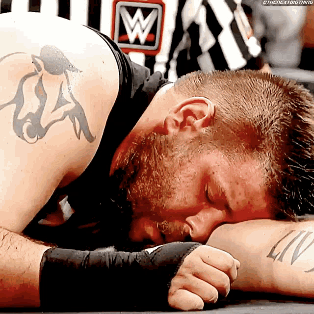 a man with a tattoo on his arm is laying down with a w on his shirt