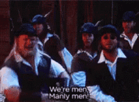 a group of men are standing in a line and one of them says we 're men manly men