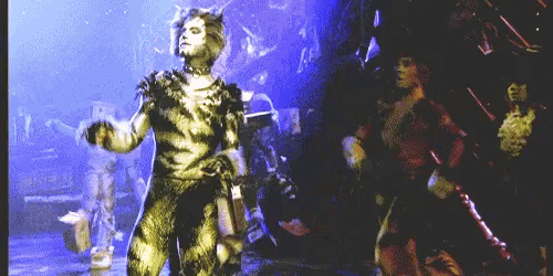 a man in a cat costume is dancing with a woman in a red dress