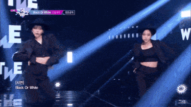 two women are dancing on a stage with the words black or white on the screen behind them