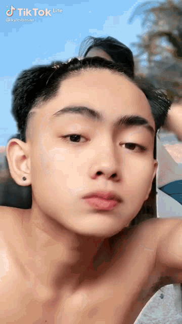 a young man without a shirt is looking at the camera with a serious look on his face .