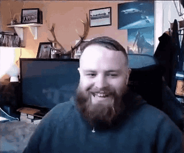 a man with a beard is smiling in front of a computer screen