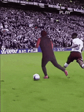 a man kicking a soccer ball on a field with a sign that says play in the background