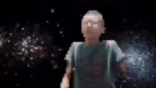 a man in a blue shirt is standing in front of a galaxy giving a thumbs up .