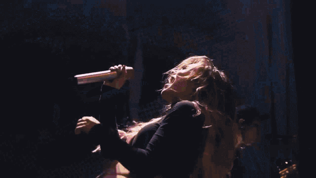 a woman is laying on her back on a stage with a drummer in the background